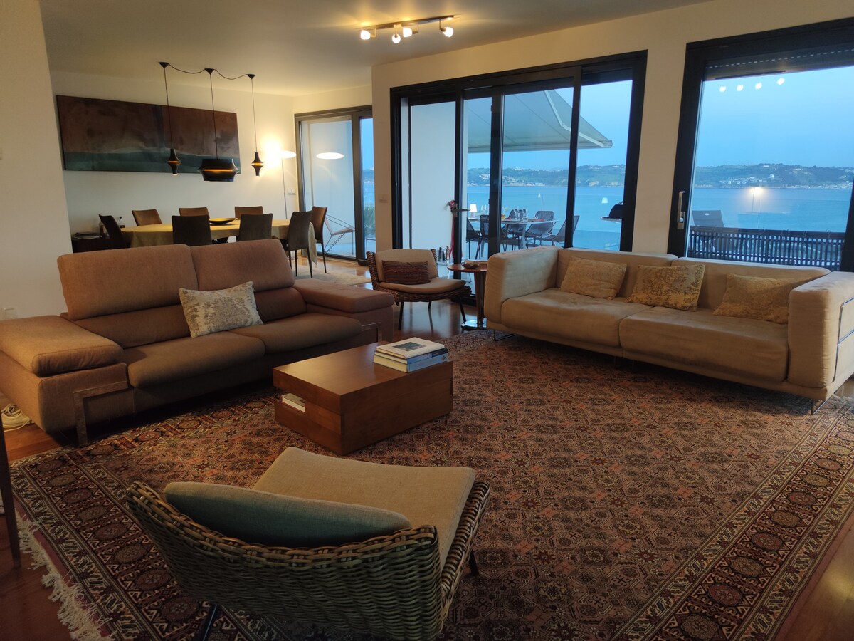 Sala com sofás, tapete e vista para o rio ao entardecer