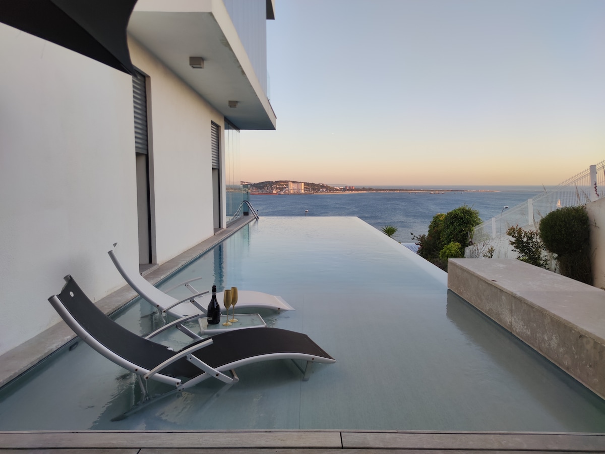 Piscina infinita ao entardecer com espreguiçadeiras e vista para o rio
