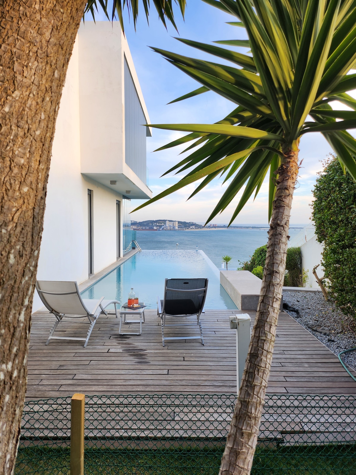 Terraço em madeira junto à piscina, entre palmeiras