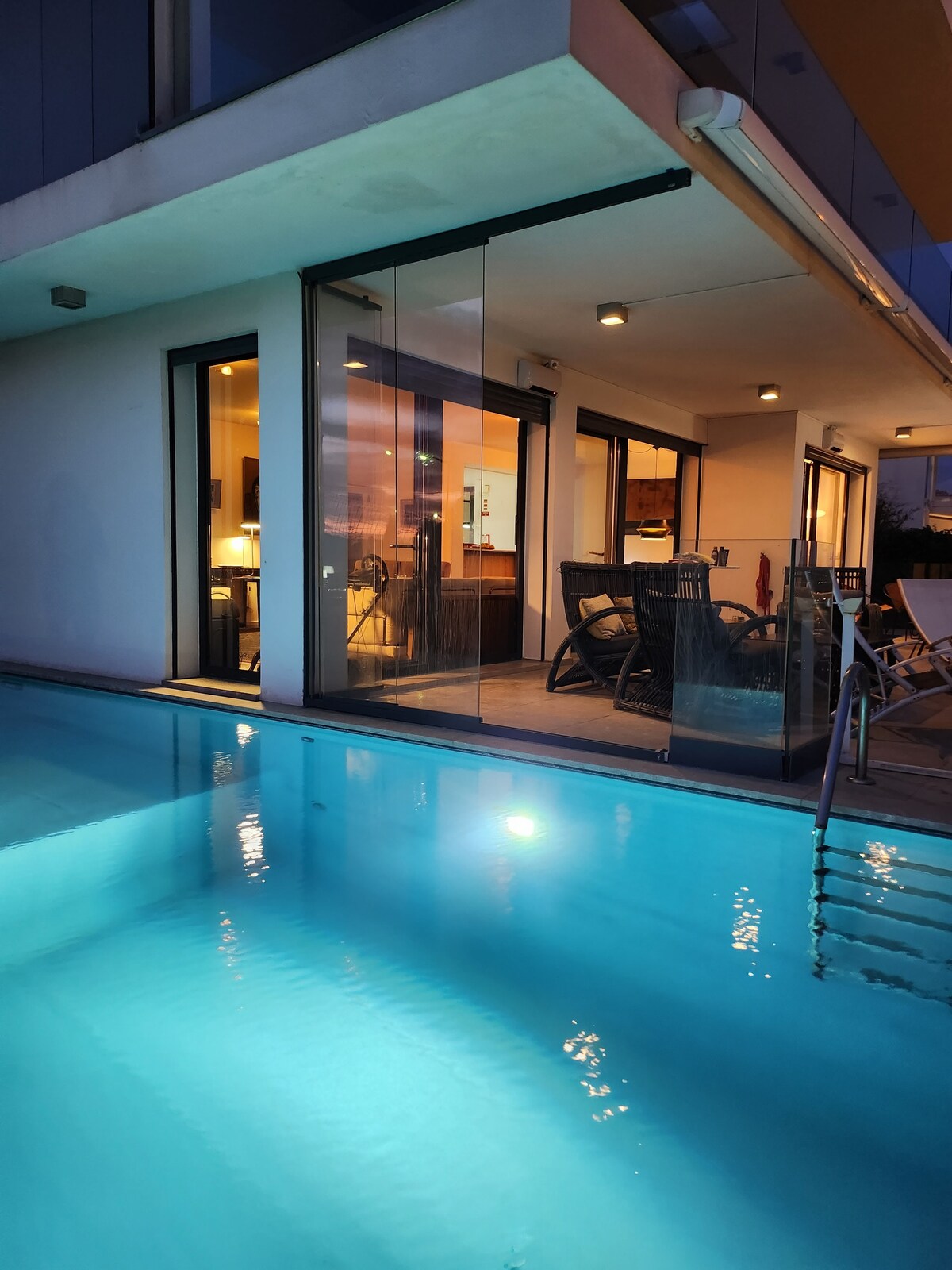 Piscina iluminada à noite junto à sala envidraçada